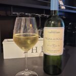 ein Glas Weißwein neben der Flasche