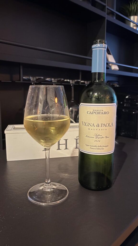 ein Glas Weißwein neben der Flasche