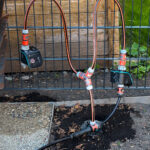 Testinstallation für die geplante Bewässerungsanlage in unserem kleinen Garten - Schläuche führen von der Wassersteckdose im Boden zu einem Verteiler und von dort zu zwei Gardena - Schaltventilen