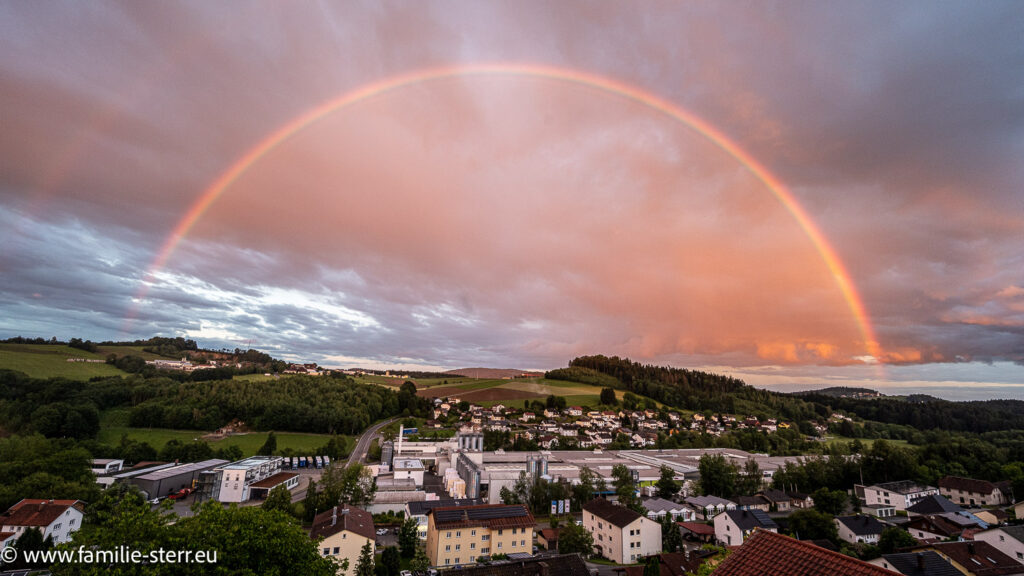 wunderschöner vollständiger Regenbogen über dem kleinen Ort Röhrnbach im Bayerischen Wald vom Hotel Jahgdhof aus gesehen