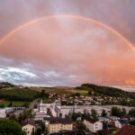 wunderschöner vollständiger Regenbogen über dem kleinen Ort Röhrnbach im Bayerischen Wald vom Hotel Jahgdhof aus gesehen